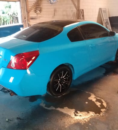 a custom blue car in a garage with a custom blue car with black custom rims
