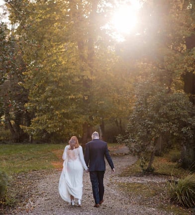 Bride and groom walk towards a sunset on their wedding day