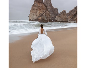 a woman in a white dress is walking along the beach