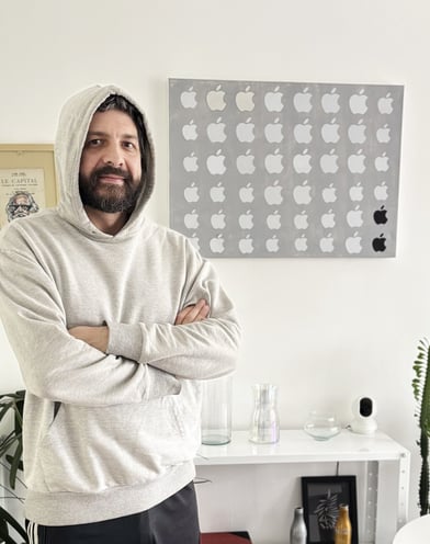 foto do duh vestindo um moleton cinza claro com capuz e uma calça preta, ao lado de seu quadro obsolescência programada .