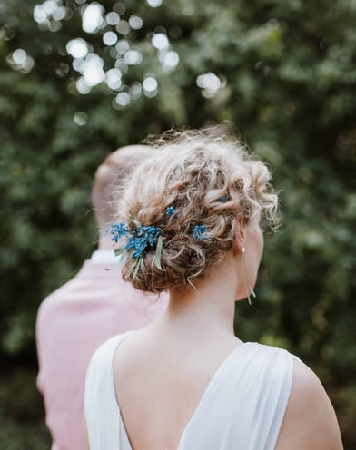 curly bride wears beautiful updo with natural blue flowers