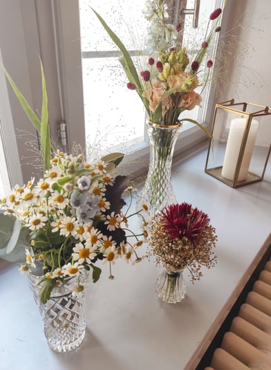 Goldene Laterne und blau orangene Blumen in Vasen auf einer Fensterbank 