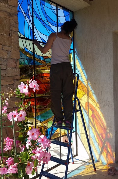 a woman is painting a stained glass window