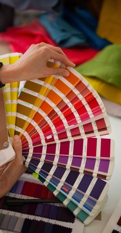 Mão segurando uma cartela com muitas cores possíveis para personalização da estampa das camisetas e