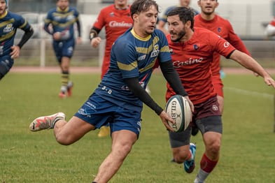 Joueur de rugby qui court et va faire une passe avant de se faire plaquer.