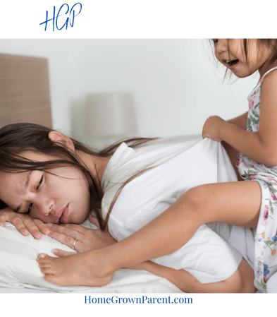 Mother in bed exhausted with small daughter on her back