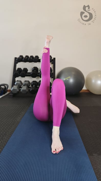 Fit woman wearing pink Alphalete leggings doing legs stretches