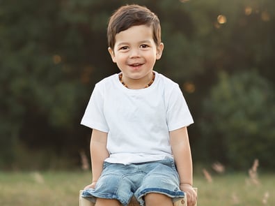 a young boy sitting on a wooden chair