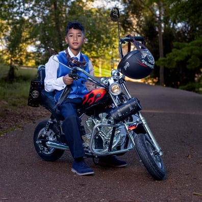 niño comunion montado en su moto  roja y  negra        