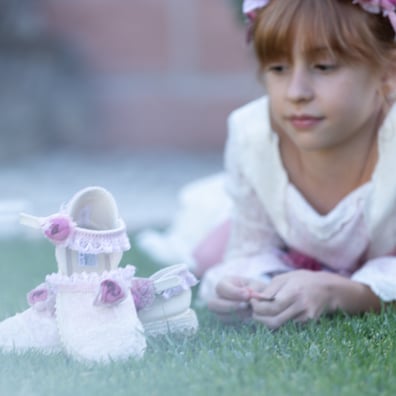 niña vestida de comunion mira sus zapatos  