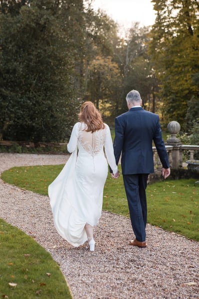 Bride and Groom walk towards a forest on their wedding day