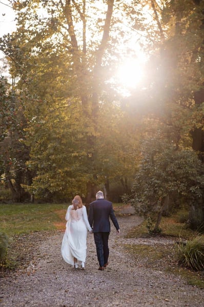 Bride and groom walk towards a sunset on their wedding day