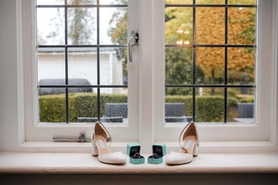 A bride's wedding shoes photographed next to her wedding ring