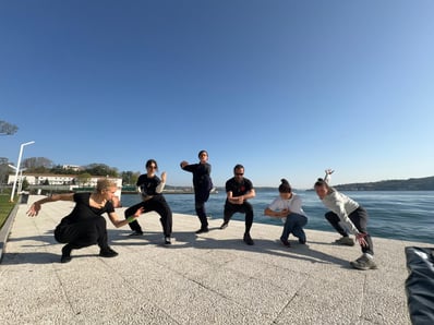 WDP instructors hold dynamic stances by İstanbul's Bosphorus sea under a clear sky, April 2025