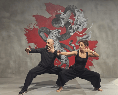 İsmet Himmet and Tuğba Türel mirror a fierce Ban Ma Bu stance before a dragon and tiger mural, embodying balance and power