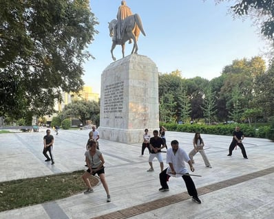 Mehmet Başkak leading a Wudang sword class in front of the İnönü statue at a public park in İstanbul.