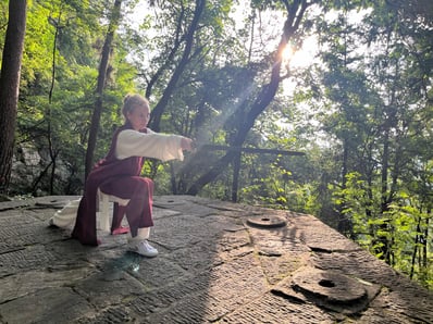 In forest stillness, Nihan Gencer holds a pointed sword on the Zhang Sanfeng Bagua stone path.