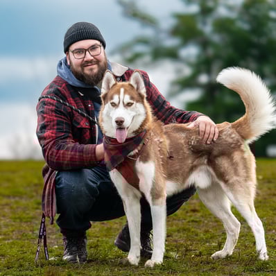 Husky leading the way with his owner behind him