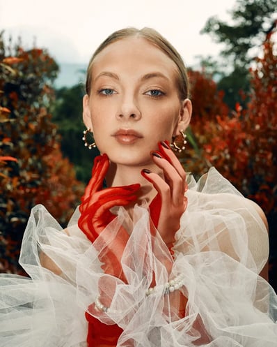 Portrait of model in a white lace top, highlighting tulle gloves and golden earrings, styled for a fashion editorial.