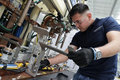 Fotografía de procesos productivos mostrando empleados trabajando en línea de producción