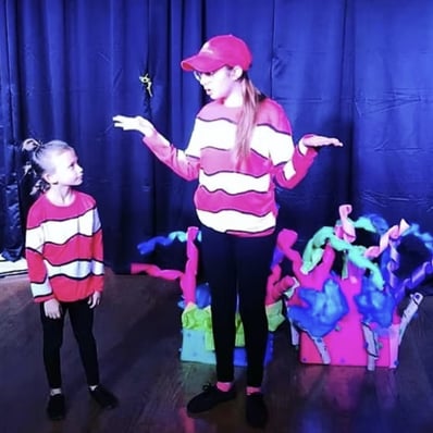 Kid actors in a musical written by a teen playwright presented at the KidWorks Festival in colorful costumes.