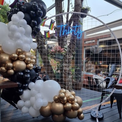 30th birthday party setup at the Brunswick Hotel with a white circle backdrop Thirty neon sign and balloon garland