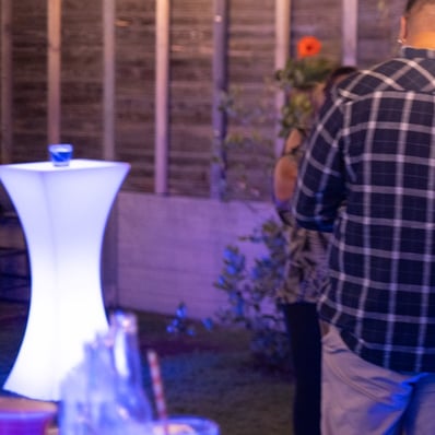Backyard house party in Redlands with guests standing to the side and an LED glow cocktail table behind.