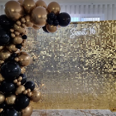 Gold shimmer wall with matching gold and black garland for sweet 16 in Brisbane.