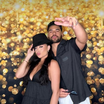 Two guests posing in front of the gold sparkle backdrop in the SweetAz Co. open air photo booth at Kaea's 21st birthday party