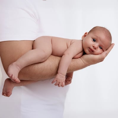 bébé porté sur le bras de son papa avec ses grands yeux ouverts