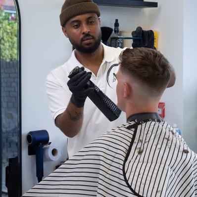 Barber spraying the hair of a customer  while he is sitting in a barber chair