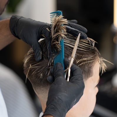 Barber combing and cutting a kids hair that has blond highlights while wet.