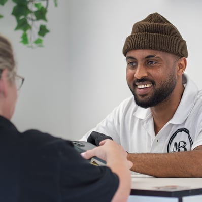 Colour image of barber tending to customer who wants to pay at the front desk