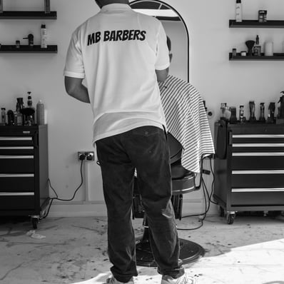 black and white image of barber with company T-shirt grooming a customer