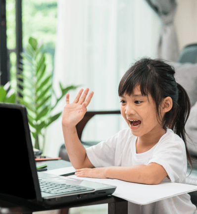 a young girl sitting at a table with a laptop