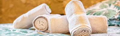 Plan serré sur des serviettes pliées avec soin, posées sur un lit dans une chambre d’hôtes
