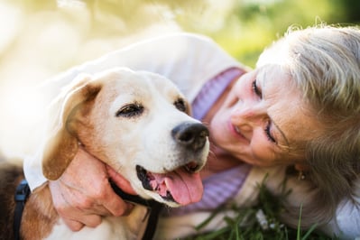 a woman is laying on the grass embracing her dog