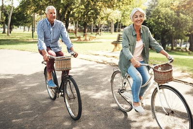 an older man and woman riding bicycles in a park
