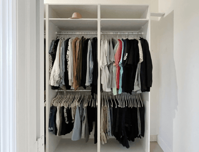Double-section wardrobe with color-coordinated clothes neatly hung on matching white hangers.
