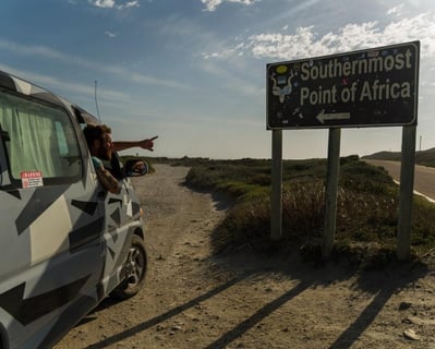 man in car looking at sign to southermost tip of africa