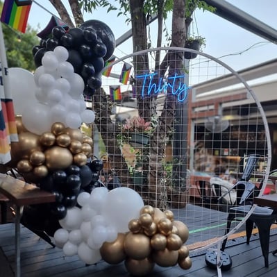 Birthday party setup at the Brunswick Hotel, white circle backdrop, neon sign and garland.