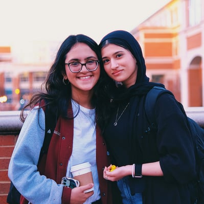 Two young college women best friends smiling at the camera.