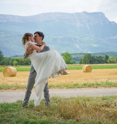 Photo de mariage, le marié porte la mariée dans ses bras dans un champ