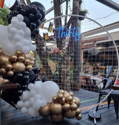 30th birthday party setup at the Brunswick Hotel with a white circle backdrop Thirty neon sign and balloon garland
