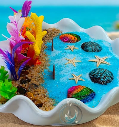 Handcrafted soy wax candle in a white shell with vibrant coral, starfish, and sea decor for home