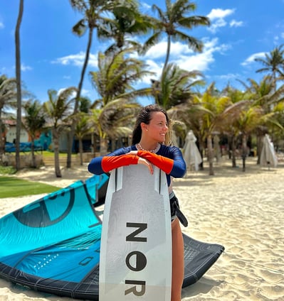 mulher com prancha de kitesurf na praia.