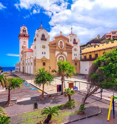 a church with a clock tower and palm trees in Candelaria