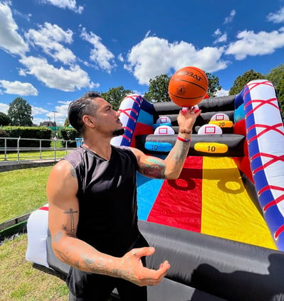 a man holding a basketball ball and a basketball inflatable court