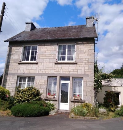 Stone holiday home with a small garden featuring rose bushes and greenery, offering a cosy countrysi
