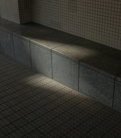 Sunlight casting shadows on a concrete tiled seating area and wall.